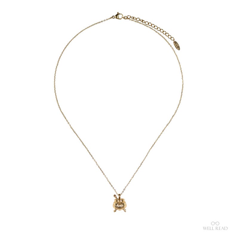 Puede incluir: Un collar dorado con un peque&ntilde;o colgante. El colgante tiene un dise&ntilde;o detallado con un elemento central y adornos. La cadena es fina y ajustable, con un cierre de broche.