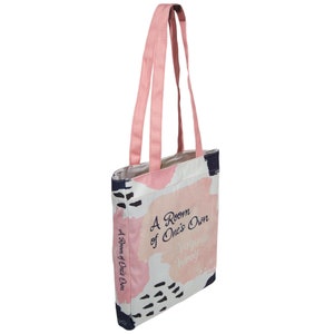 May include: A pink canvas tote bag with a white background and abstract pink and blue brushstrokes. The bag has two pink straps and features the text "A Room of One's Own" by Virginia Woolf.