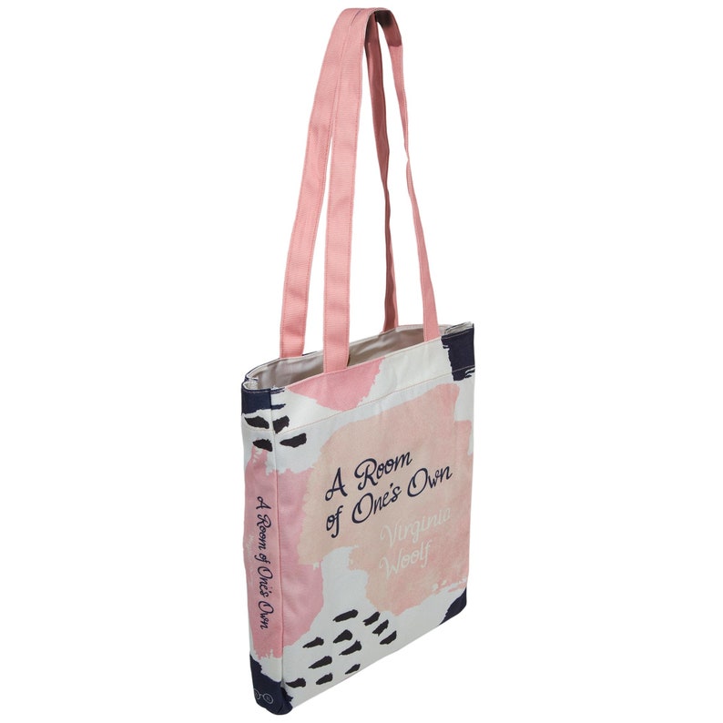 May include: A pink canvas tote bag with a white background and abstract pink and blue brushstrokes. The bag has two pink straps and features the text "A Room of One's Own" by Virginia Woolf.