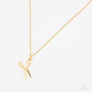 Peut inclure: Un collier en cha&icirc;ne dor&eacute;e avec un pendentif en forme de ciseaux dor&eacute;s.