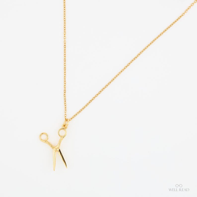 Peut inclure: Un collier en cha&icirc;ne dor&eacute;e avec un pendentif en forme de ciseaux dor&eacute;s.
