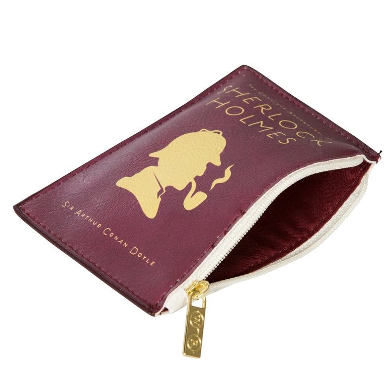 Puede incluir: Una bolsa de cremallera color burdeos con una silueta dorada de Sherlock Holmes y el texto "The Complete Adventures of Sherlock Holmes" y "Sir Arthur Conan Doyle".