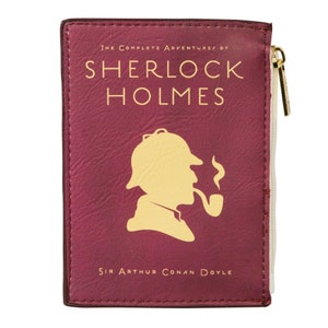 Puede incluir: Una bolsa de cremallera color burdeos con una silueta de Sherlock Holmes con un sombrero de cazador y fumando una pipa. El texto "The Complete Adventures of Sherlock Holmes" y "Sir Arthur Conan Doyle" est&aacute; impreso en dorado en la parte delantera.