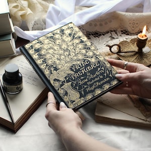 May include: A hardcover edition of "Pride and Prejudice" by Jane Austen, illustrated by Hugh Thomson. The book features a black cover with gold peacock feather and floral designs. The title is prominently displayed in elegant script.