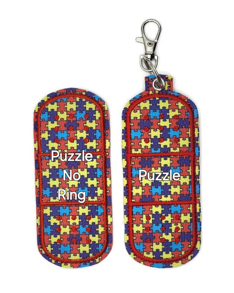 May include: Two red, yellow, blue, and purple puzzle piece patterned fabric keychains. One keychain has the text "Puzzle No Ring" and the other keychain has the text "Puzzle".