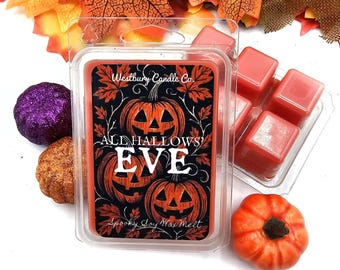 May include: A clear plastic clamshell container filled with orange wax melts, featuring a label with three jack-o'-lanterns and the text Westbury Candle Co. ALL HALLOWS' EVE Spooky Soy Wax Melt, surrounded by decorative artificial autumn leaves.