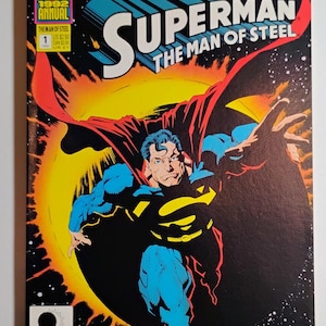 Puede incluir: Portada de cómic de "Superman: The Man of Steel" con Superman en una pose dinámica sobre un fondo oscuro y estrellado. La portada incluye el texto "Eclipso: The Darkness Within" y "1992 Annual".