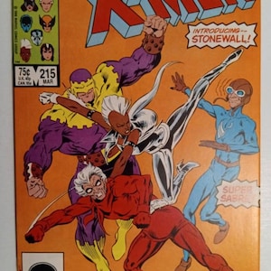 Peut inclure: Une couverture de bande dessinée mettant en scène les X-Men. La couverture présente Tornade, Sabretooth et Crimson Commando. La couverture est orange avec le titre "The Uncanny X-Men" en grandes lettres blanches. Le numéro du numéro est 215.