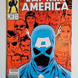 May include: A comic book cover with the title "WHO WILL BE THE NEXT CAPTAIN AMERICA" in white letters on an orange background. The cover features a blue Captain America figure with a large "A" on the forehead, surrounded by various faces. The Marvel logo is in the upper left corner.
