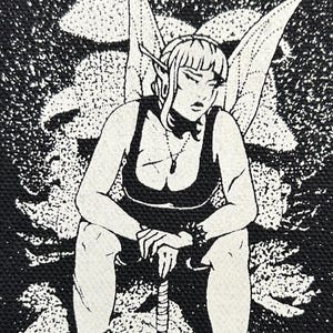 May include: Black and white patch featuring a seated fairy with pointed ears and wings, holding a spiked weapon. The fairy wears a tank top and boots. The artist's name and year, "Leitzer 2023", are printed at the bottom.