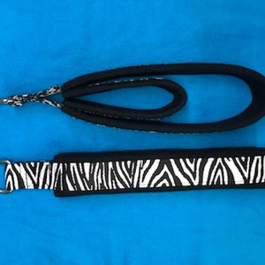 May include: Two black and white zebra print dog collars with silver metal D-rings. The collars are made of a soft, padded material.