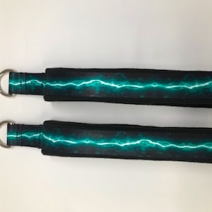 May include: Two black exercise straps with a teal lightning bolt design and silver metal rings.