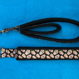 May include: A black dog leash with a colorful sugar skull pattern. The leash has a black handle and a silver clip.