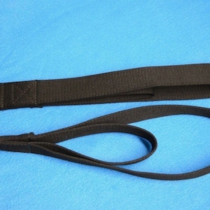 Op de afbeelding: Twee zwarte nylon banden met zilveren metalen ringen aan het ene uiteinde. De banden zijn van verschillende lengtes.
