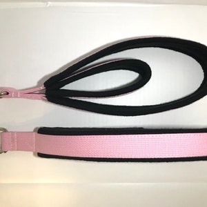 May include: Two pink and black fabric straps with metal rings at one end. The straps are designed for fitness or exercise.