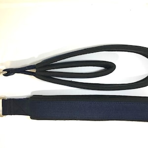 May include: A blue and black dog leash with a metal ring on each end. The leash is made of a soft, padded material.