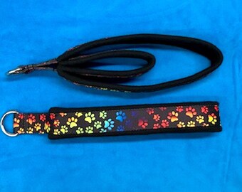 May include: A black dog leash with a rainbow paw print pattern. The leash has a loop handle and a metal clip.