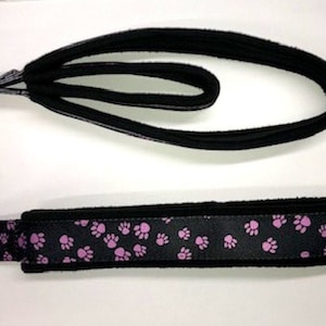 May include: Two black dog leashes with pink paw print designs. One leash is a loop and the other is a flat leash.