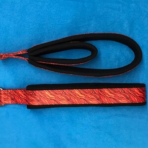 May include: Two black and red dog leashes with a red and orange wavy pattern. One leash is a loop and the other is a flat strap.