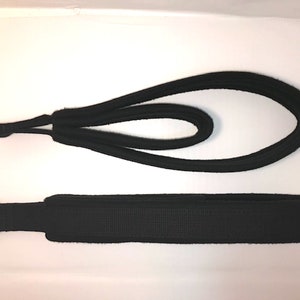 May include: Two black fabric straps with metal rings at one end. The straps are designed for fitness exercises.