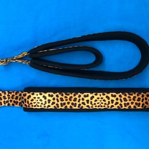 May include: A black and leopard print dog leash with a metal ring on each end.