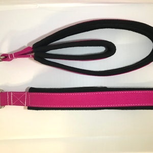 May include: Two pink and black fabric straps with metal rings at one end. The straps are designed for exercise and fitness.