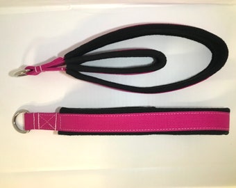 May include: Two pink and black fabric straps with metal rings at one end. The straps are designed for exercise and fitness.