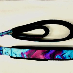 May include: A black and blue dog leash with a padded handle and a silver metal ring. The leash has a blue and purple abstract pattern.