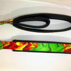May include: Two black and green dog leashes with silver metal rings. The leash on the bottom has a colorful abstract pattern with red, yellow, and green swirls.