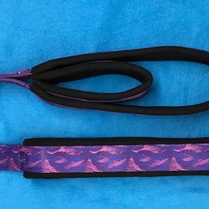 Puede incluir: Dos collares para perros de color morado y negro con un patrón de ondas. Los collares están hechos de un material suave y acolchado y tienen un anillo de metal para sujetar una correa.