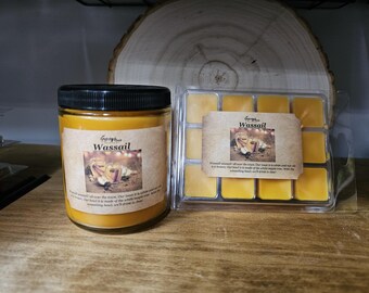 May include: A yellow candle with a black lid and a label that reads "Greyfriar Wassail". The candle is next to a clear plastic tray of yellow wax melts. The label on the wax melts also reads "Greyfriar Wassail".  The label describes the scent as "Wassail, all over the room.  Our room is in white maple and our air is citrus. Our blend is made of the whole maple tree. With the overwhelming scent, we'll drink in cheer."