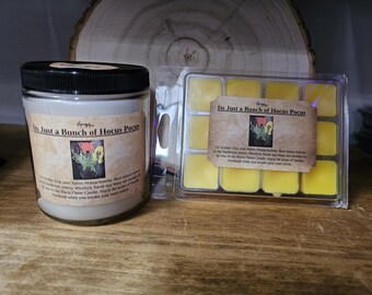 May include: Two candles with the text "Its Just a Bunch of Hocus Pocus" on the label. The candles are in a clear glass jar and a yellow wax melt tray.