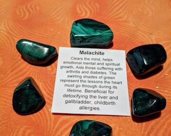 May include: A collection of green malachite stones with a card that reads "Malachite" and describes the stone's properties. Clears the mind, helps emotional mental and spiritual growth. Aids those suffering with arthritis and diabetes. The swirling shades of green represent the lessons the heart must go through during its lifetime. Beneficial for detoxifying the liver and gallbladder, childbirth allergies.