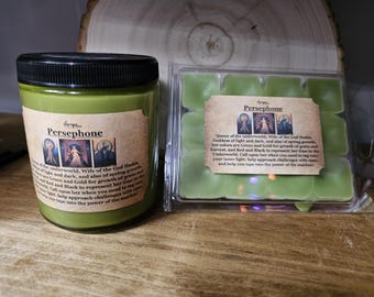May include: Two green candles with labels that read "Persephone" and describe her as the Queen of the Underworld, Wife of the God Hades, Goddess of light and dark, and also of spring growth. Her colors are Green and Gold for growth of grain and harvest, and Red and Black to represent her time in the Underworld. Call upon her when you need to tap into your inner light, help approach challenges with grace, and help you tap into the power of the maiden.