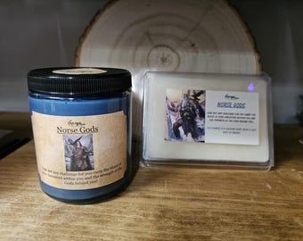 May include: A blue candle in a jar with a black lid and a white wax melt in a clear container. Both items have labels with the text "Norse Gods" and an illustration of a warrior. The candle label includes the text: "Face not any challenge for you carry the blood of your ancestors within you and the strength of the Gods behind you!"