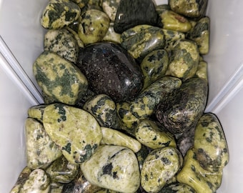 May include: A collection of green and black tumbled stones. The stones are smooth and polished, with a variety of patterns and textures.