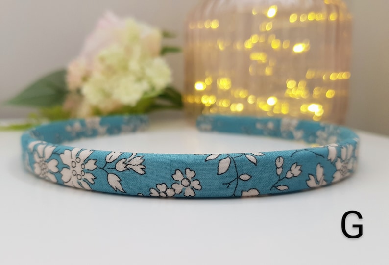 May include: A blue headband with a white floral pattern. The headband is made of fabric and has a simple design.