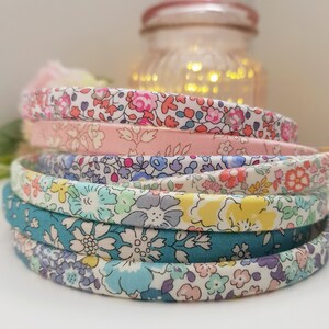 May include: A stack of five colorful fabric headbands with floral patterns. The headbands are made of a soft, stretchy fabric and are perfect for adding a touch of style to any outfit.