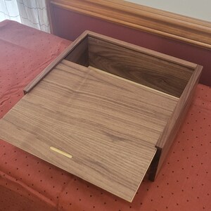 May include: A wooden box with a hinged lid, made of walnut wood with a natural finish. The lid is open, revealing the empty interior of the box.