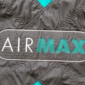 May include: Close-up of a black and teal jacket with a white "AIR MAX" logo patch.