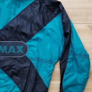 May include: A teal and black windbreaker jacket with a large "MAX" logo on the front. The jacket has a zipper closure and a drawstring hood.