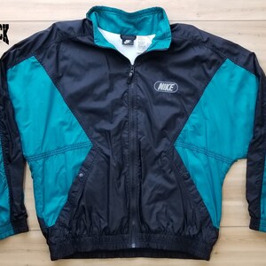 May include: Black and teal Nike windbreaker jacket with a zipper closure and the Nike logo on the front.