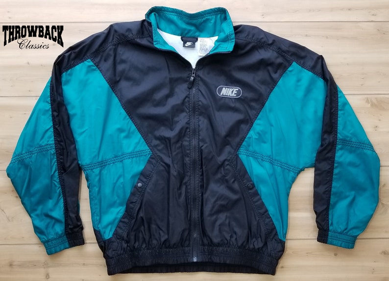 May include: Black and teal Nike windbreaker jacket with a zipper closure and the Nike logo on the front.