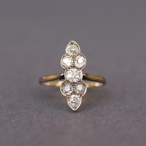 May include: A silver ring with a row of five round diamonds set in a pointed shape.