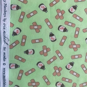 May include: Light green fabric with a repeating pattern of brown bandages, brown cross-shaped bandages, and dark brown medicine bottles with an "R" symbol. The text "5 Funky Monkeys by erin michael for moda" is printed on the left side.