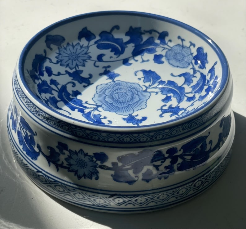 以下が含まれることがあります： 青と白の花柄が施された白い陶器のボウル。ボウルは縁が高く、波打った縁をしています。