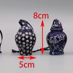 May include: Three blue and white ceramic ornaments with floral designs. The ornaments are 6 cm wide and 7 cm tall, 5 cm wide and 8 cm tall, and 6 cm wide and 8 cm tall.