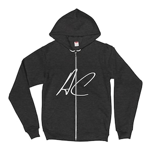 Peut inclure: Un sweat à capuche gris foncé avec un logo "AC" blanc sur le devant.