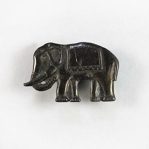 May include: A small, antique-style elephant figurine in a dark metallic finish. The elephant has detailed features, including a trunk, tusks, and a saddle. The figurine is likely made of metal and is displayed against a plain white background.