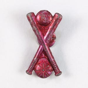 Può includere: Una spilla da baseball in stile vintage con finitura metallica invecchiata. La spilla presenta mazze da baseball incrociate e una palla da baseball, il tutto in tonalità rosse e argento. Il design è una rappresentazione classica dello sport.